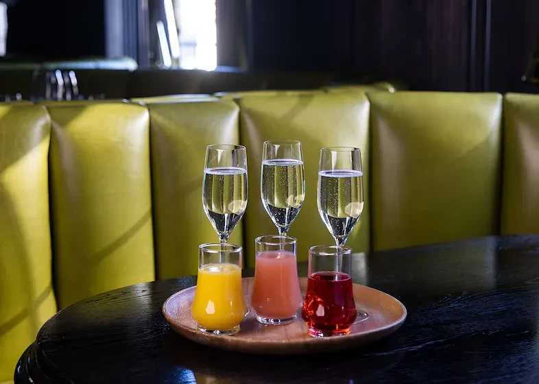 Six drinks: colorful juices topped with sparkling flutes on a tray.