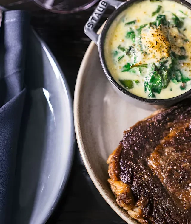 Top-down view: Seared steak, creamed spinach in cocotte, restaurant meal.
