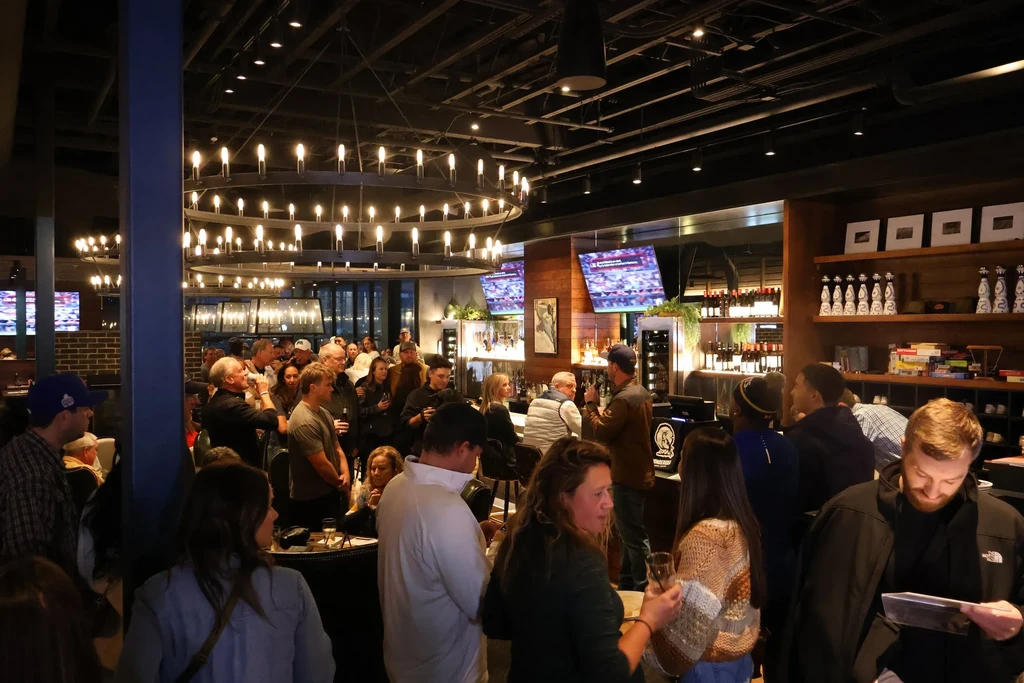 Lively crowd socializing in a modern upscale restaurant bar.