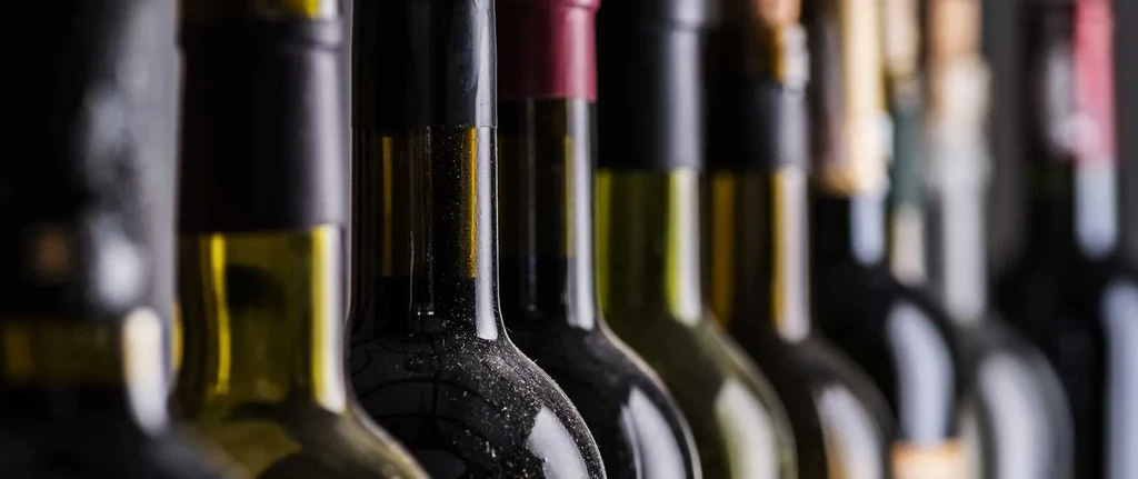 Row of dusty wine bottles in a dimly lit cellar.