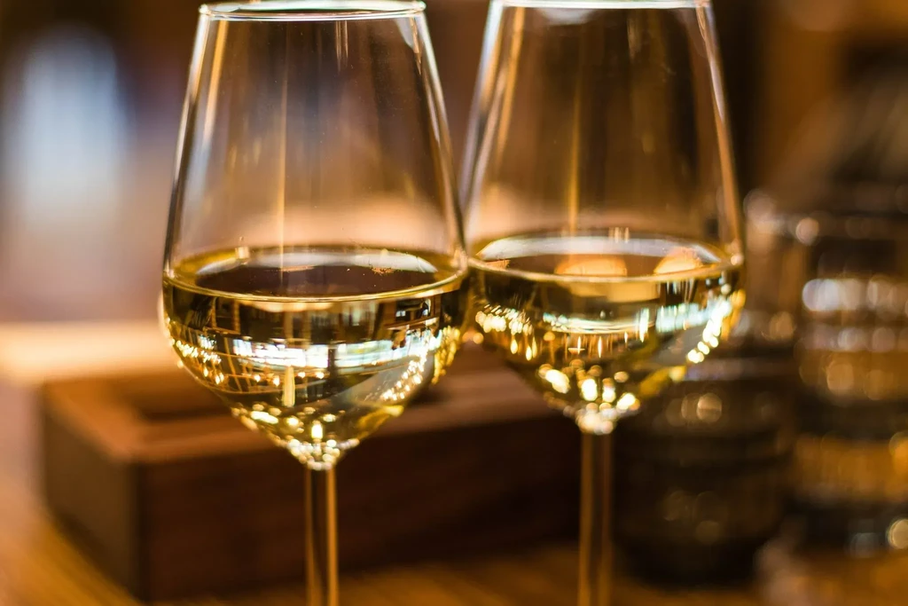 Two elegant wine glasses filled with sparkling golden white wine.