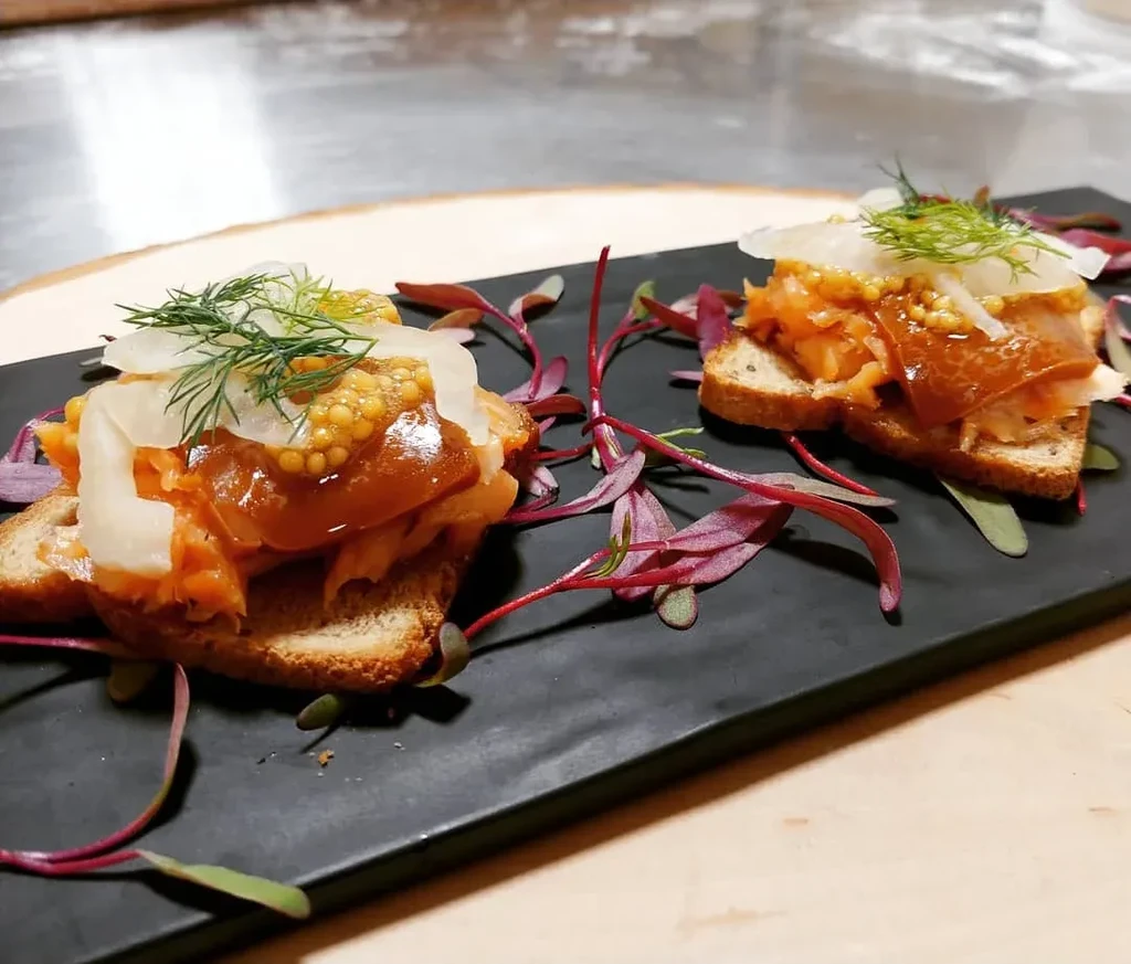 Appetizers of toasted bread, flaked fish, mustard, dill, and microgreens.