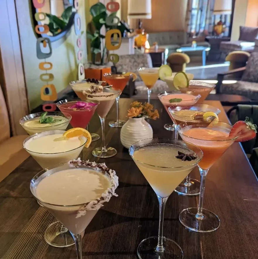 Colorful, garnished cocktails arranged on a dark table in a stylish bar.