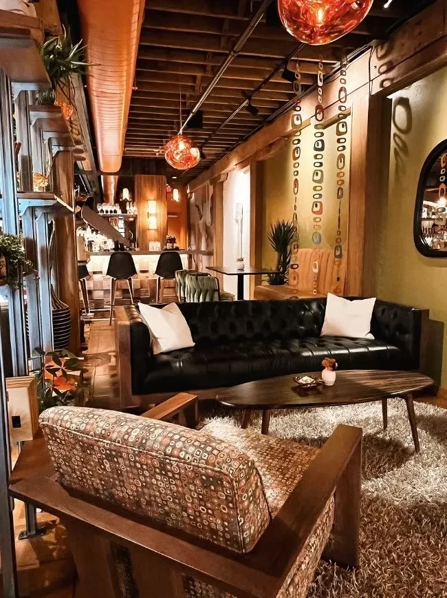 Warm-lit mid-century modern restaurant interior with lounge and bar.