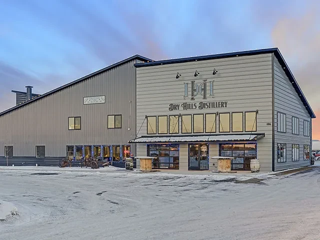 Dry Hills Distillery building exterior covered in snow during twilight.
