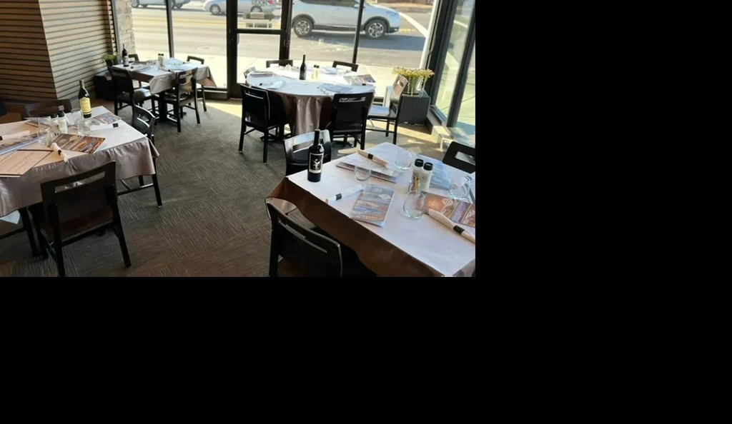 Empty restaurant dining room showing tables set under natural light.