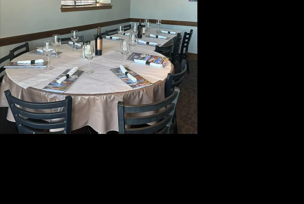 Empty restaurant dining room with two set tables and wine.