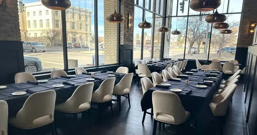 Empty modern restaurant dining room with set tables and large windows.