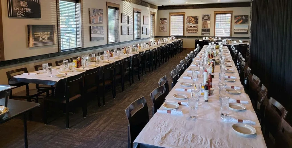 Well-lit, empty restaurant dining area with long rows of set tables.