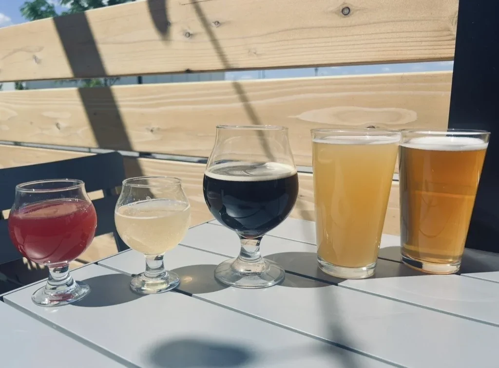 Five distinct beverages in different glasses on a sunny patio table.