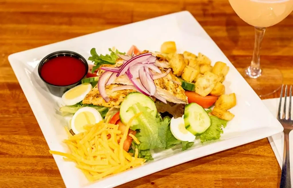 Grilled chicken salad with mixed greens, egg, cheese, and red dressing.