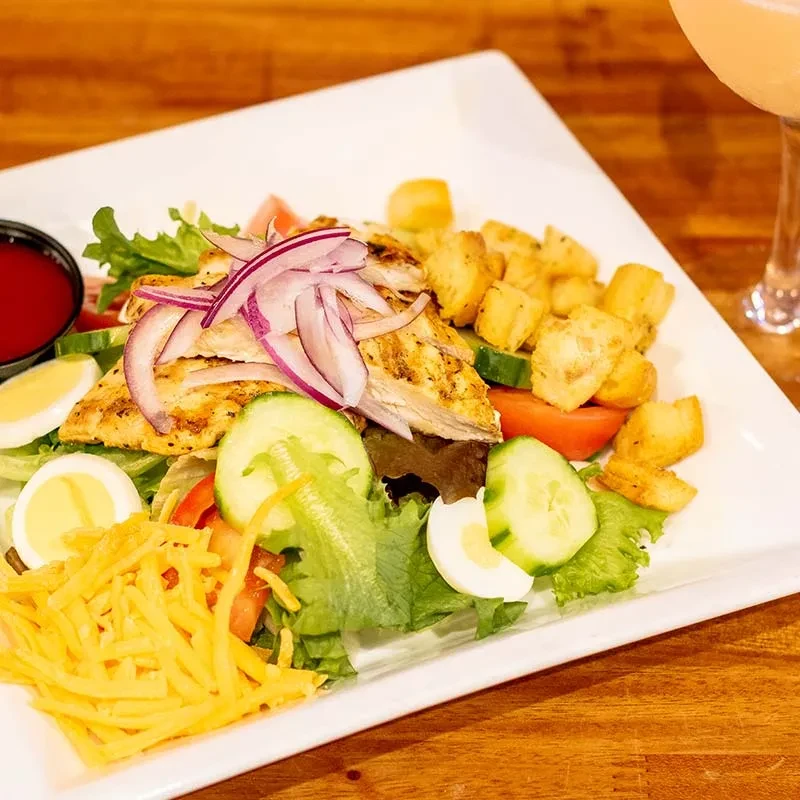 Grilled chicken salad with eggs, vegetables, croutons, and shredded cheese.