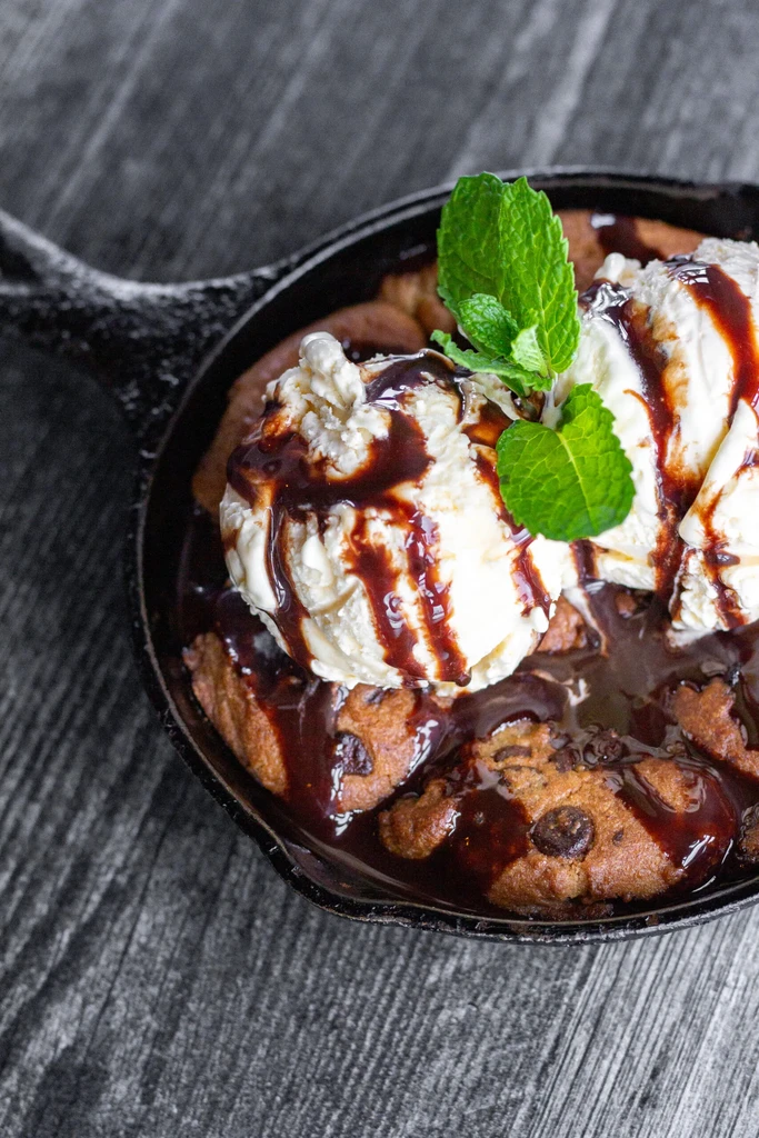 Warm chocolate cookie skillet with vanilla ice cream, sauce, and mint.