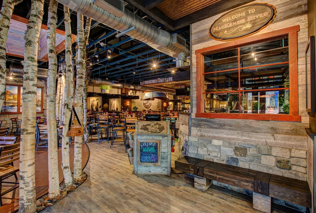 Mackenzie River restaurant: rustic-industrial interior with birch trees.