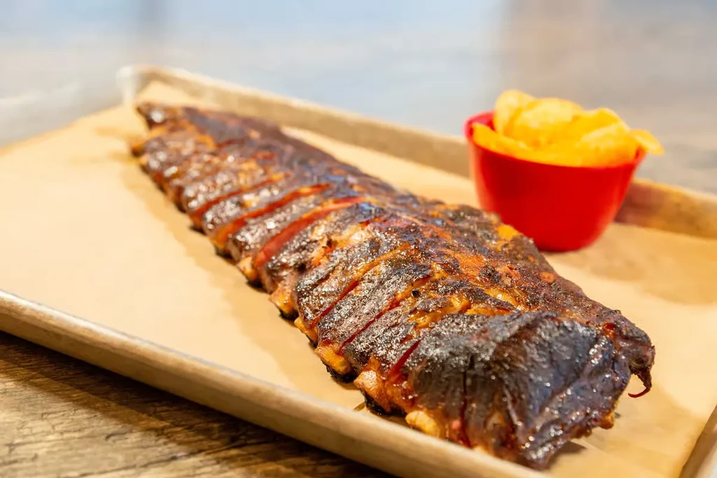 Charred, glazed ribs and chips in a red cup.