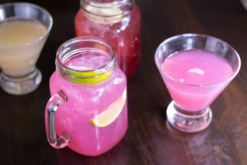 Three pink drinks, two in mason jars, one martini glass.
