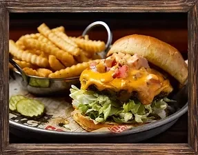 Close-up cheeseburger with melted cheese, lettuce, crinkle fries, pickles.