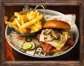 Gourmet burger with bacon, cheese, mushrooms, and crinkle-cut fries on a tray.