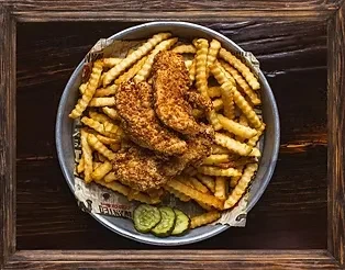 Crinkle fries, chicken tenders, and pickles served in a round metal tray.