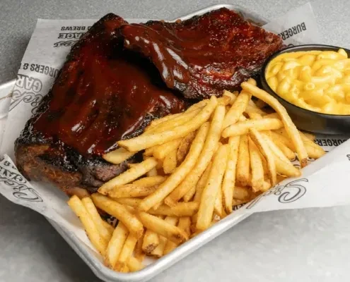 Barbecue ribs, french fries, and macaroni and cheese on a metal tray.