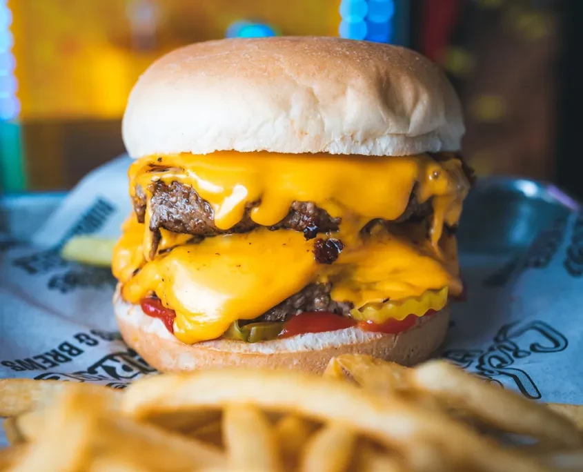 A double-patty cheeseburger with dripping melted cheese and french fries.