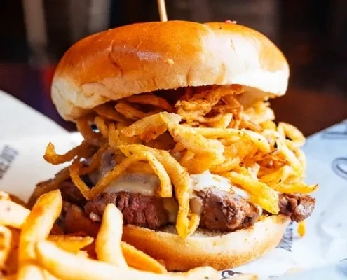 Large brioche burger with melted cheese, fried onions, and golden fries.