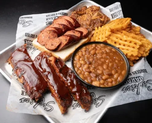 BBQ platter with ribs, sausage, pulled pork, waffle fries, and baked beans.
