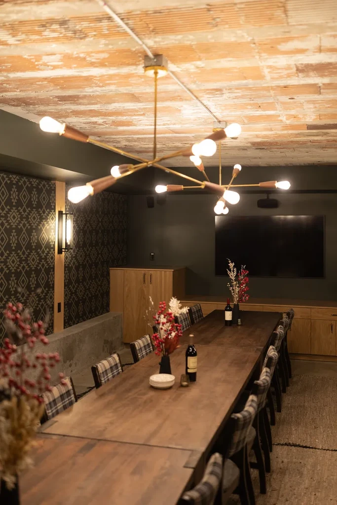Dark industrial-chic private dining room with rustic table and plaid chairs.
