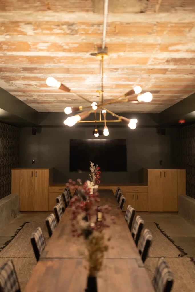 Elegant private dining room with Sputnik chandelier, long table, and plaid chairs.
