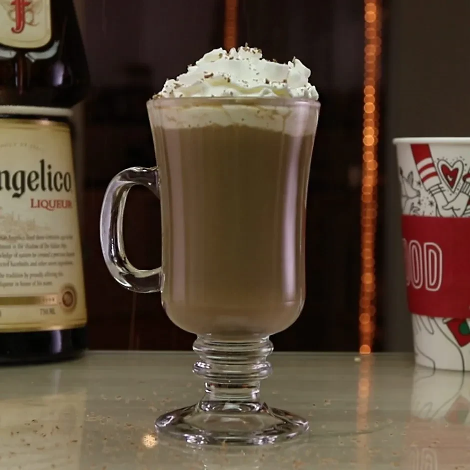 Glass mug of creamy drink, whipped cream, and Angelico Liqueur bottle.