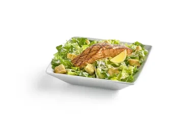 Grilled salmon Caesar salad in a white bowl with lemon.