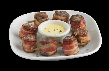 Eight bacon-wrapped meats surrounding a central dipping sauce on a plate.