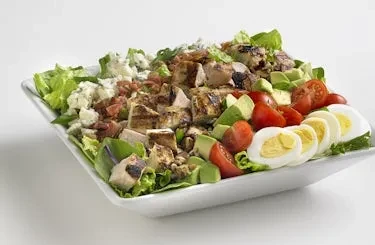 Large colorful Cobb salad with chicken, avocado, egg, tomato, and cheese.