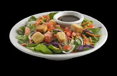 White bowl filled with a colorful salad, croutons, and dressing.
