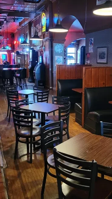 Empty, dimly lit pub interior with wooden tables and colorful neon.
