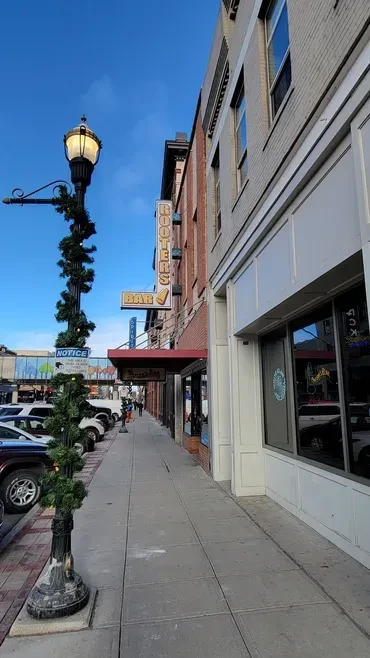 Bright urban street with Rooters Bar, parked cars, and garland.