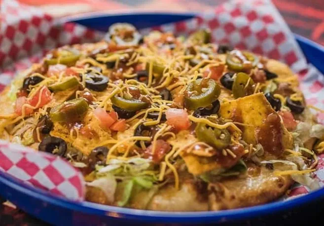 Loaded fry bread topped with cheese, olives, jalapeños, tomatoes, lettuce.