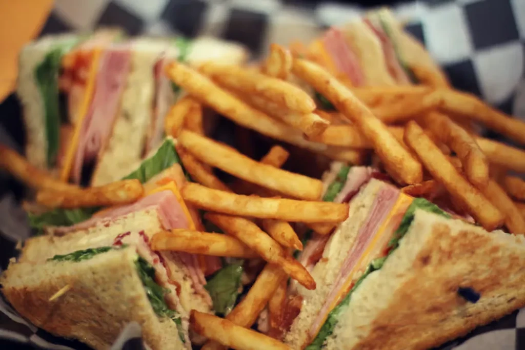 Club sandwich quarters with ham, lettuce, cheese, and golden french fries.