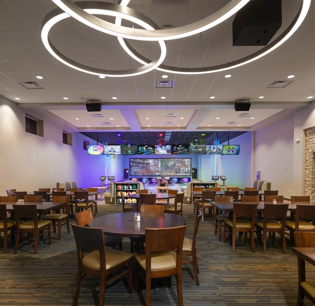 Modern entertainment venue with empty dining area and colorful bowling lanes.