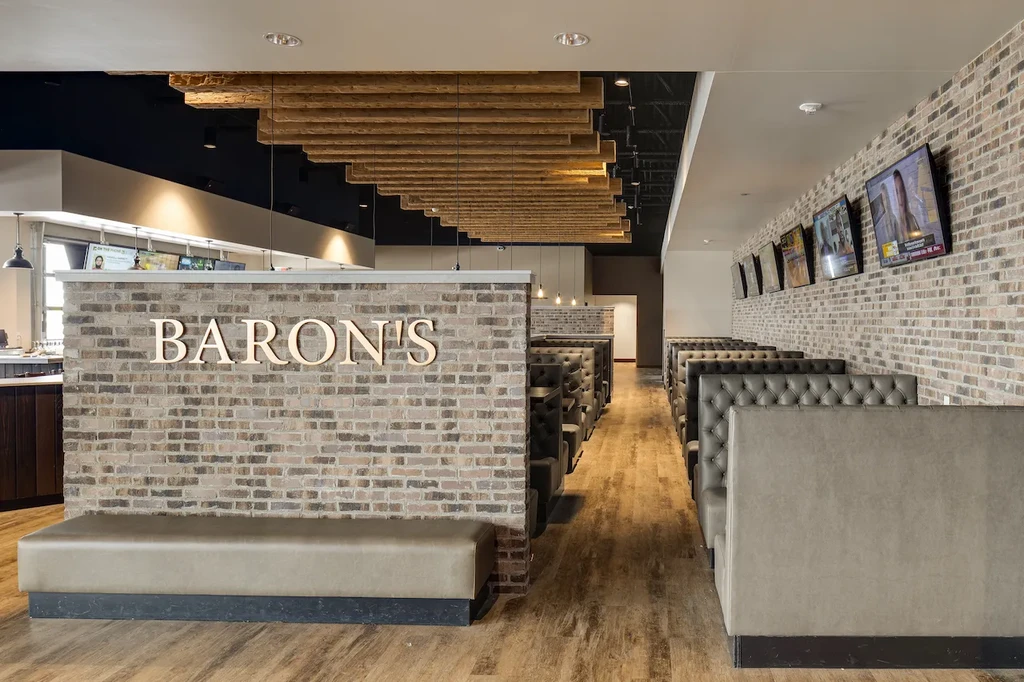 Modern Baron's restaurant interior with booths, brick walls, and wooden ceiling.