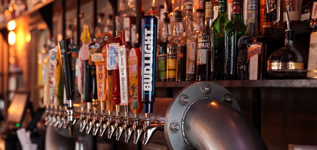 Well-stocked bar features chrome beer taps and various liquor bottles.