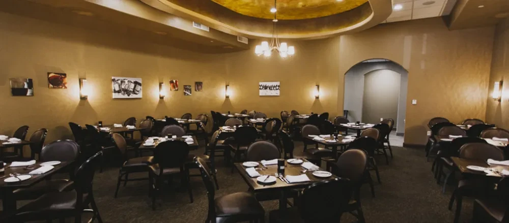 Empty restaurant dining room, set tables, art, golden dome, warm lighting.