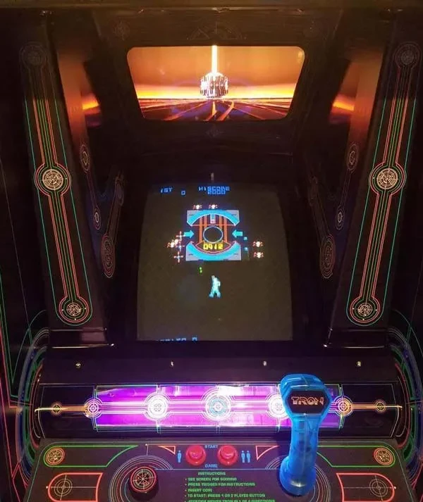 Vintage TRON arcade game machine with glowing lines and active gameplay.