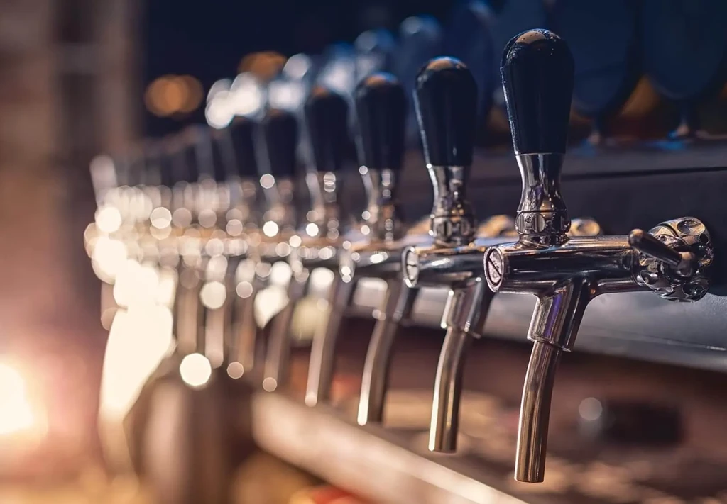 Chrome beer taps in a row with a warm, blurry background.