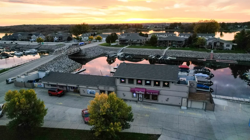 Aerial view of The Pier Bar & Grill by a marina at sunset.
