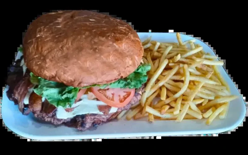 A hamburger with lettuce, tomato, bacon, cheese, and french fries.