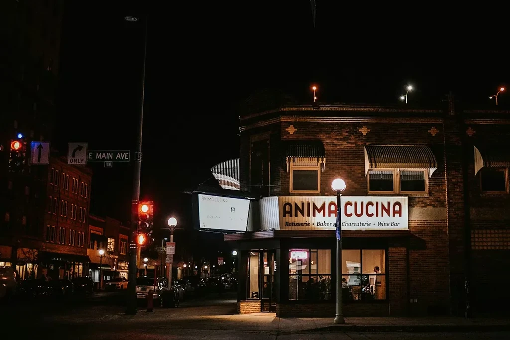 Illuminated ANIMA CUCINA brick restaurant at night on E Main Ave.