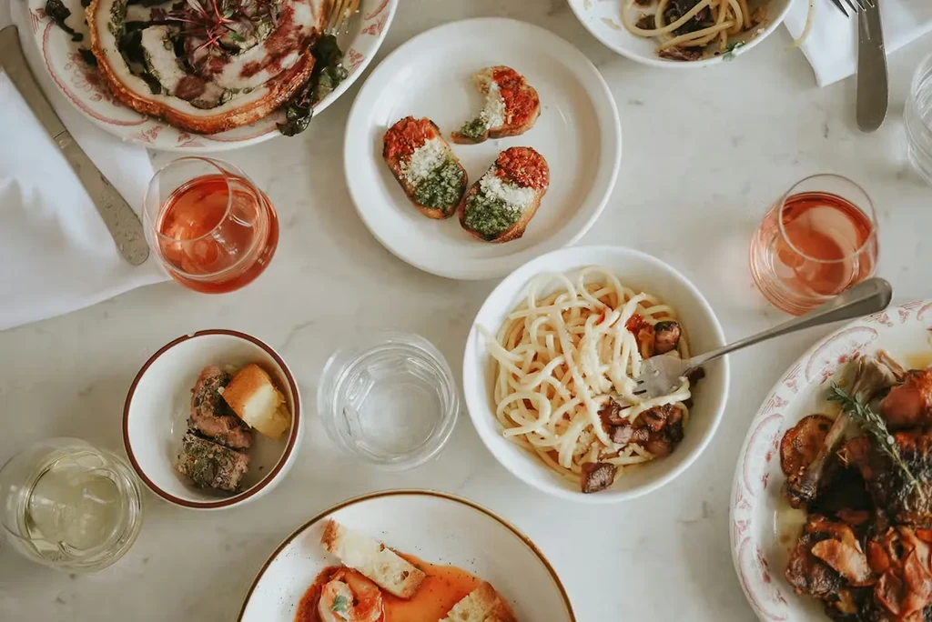 Overhead view of a dining table laden with assorted Italian dishes and drinks.