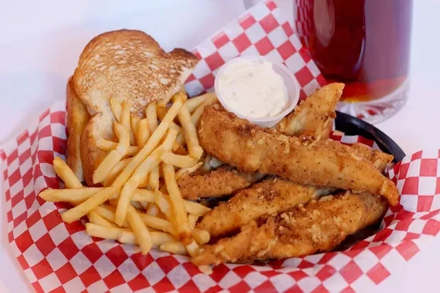 Fried fish, french fries, toast, and sauce in a diner basket.