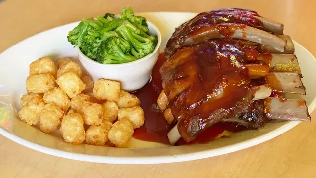 Plate of saucy barbecue ribs, tater tots, and green broccoli.